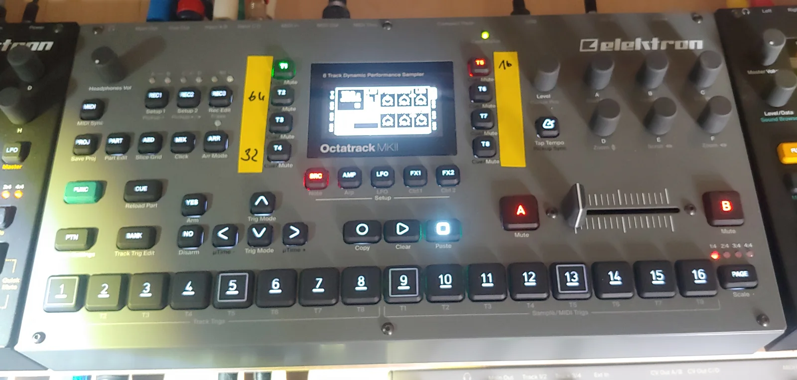 Grey Octatrack MKII front panel with its display, track controls, sequencer buttons and crossfader.